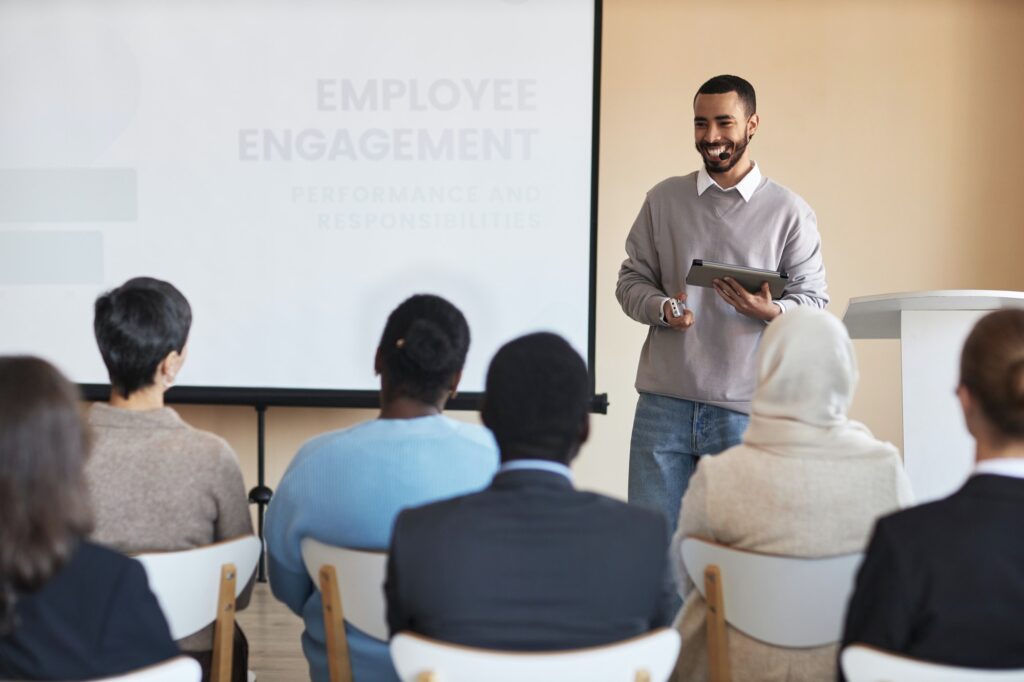 Young cheerful HR manager with tablet looking at one of employees